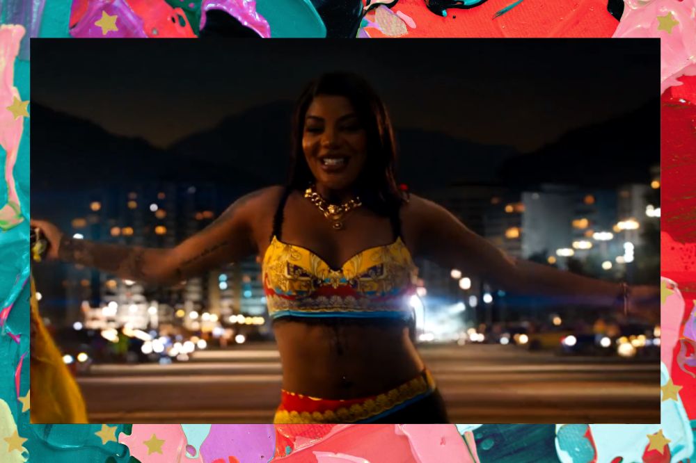 Ludmilla em cena de Velozes e Furiosos 10; ela está sorrindo enquanto segura a bandeira da corrida com os braços abertos; a margem é uma textura nas cores rosa, lilás, verde, roxo, vermelho e preto com estrelas amarelas como decoração