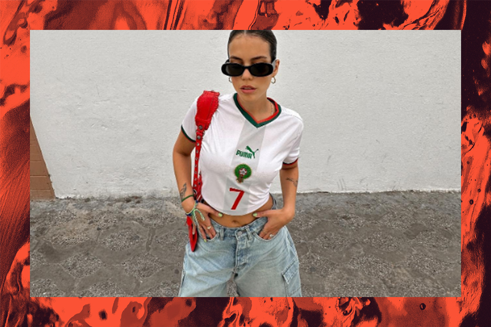 Garota usando look com camisa de time de futebol, bermuda jeans oversized e óculos de sol