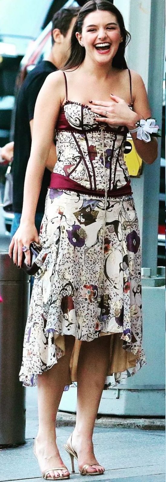 Suri Cruise aposta em vestido diferentão e moderno para formatura do ensino médio Imagem de uma jovem branca, de cabelos castanhos, vestido estampado curto, sorrindo.