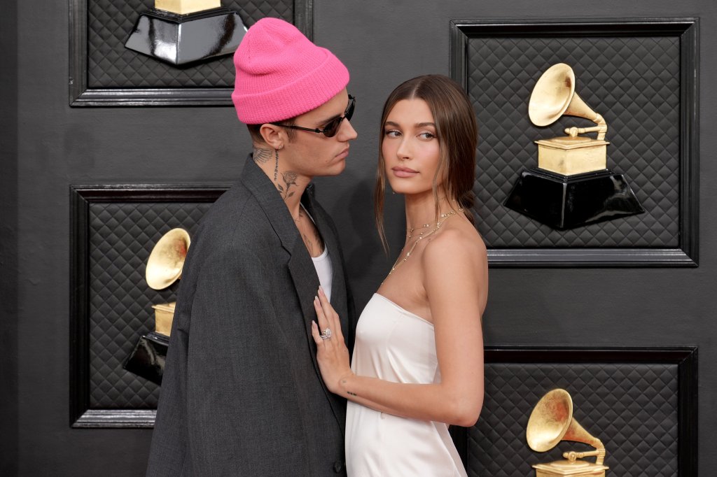 Justin Bieber e Hailey Bieber posando para foto; ela está olhando para frente enquanto o cantor a encara