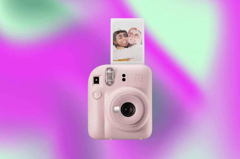 Imagem de uma máquina instax de foto rosa em um fundo roxo e verde.
