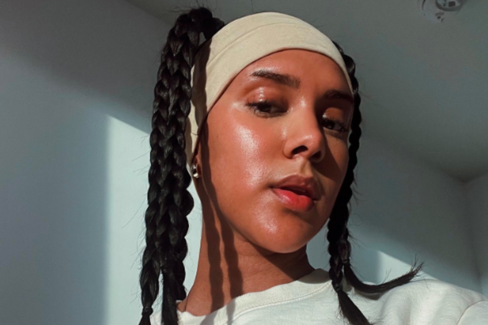 Mulher usando cabelo preso em tranças e com faixa bege