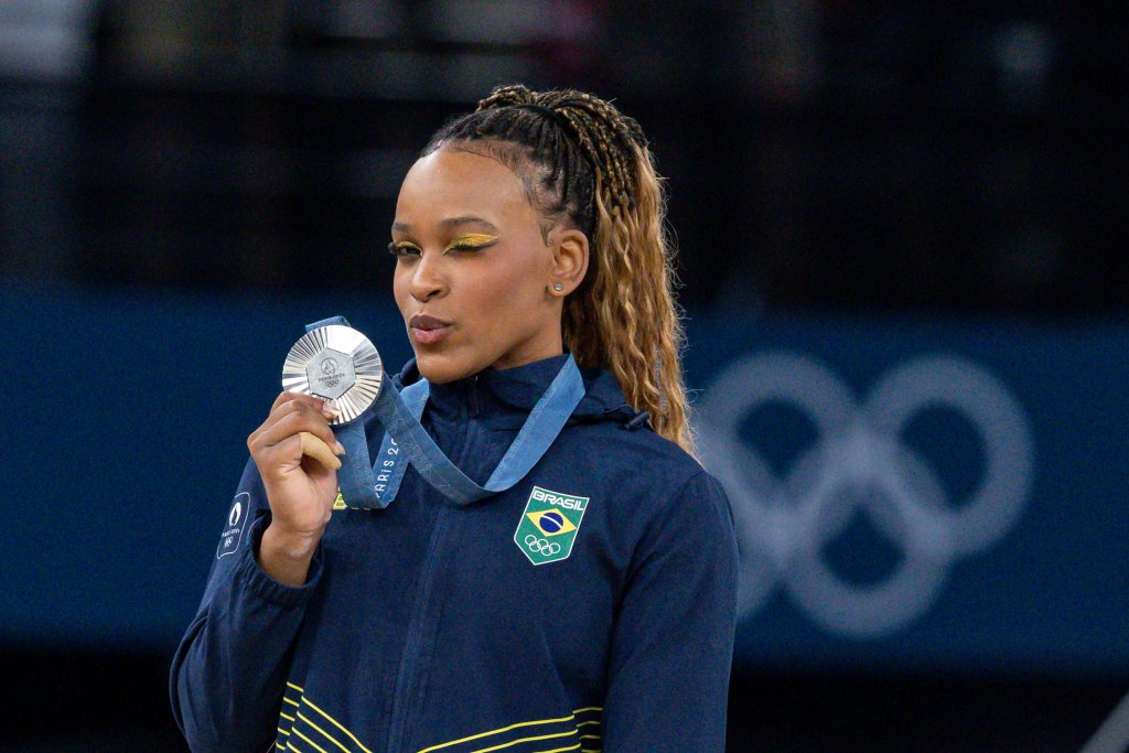 Rebeca Andrade com medalha nas Olímpiadas de Paris 2024; ela está piscando um dos olhos enquanto levanta medalha de prata