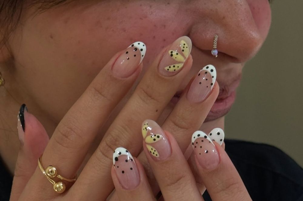 Unhas com estampa de bolinhas em preto e branco, francesinha e flor amarela
