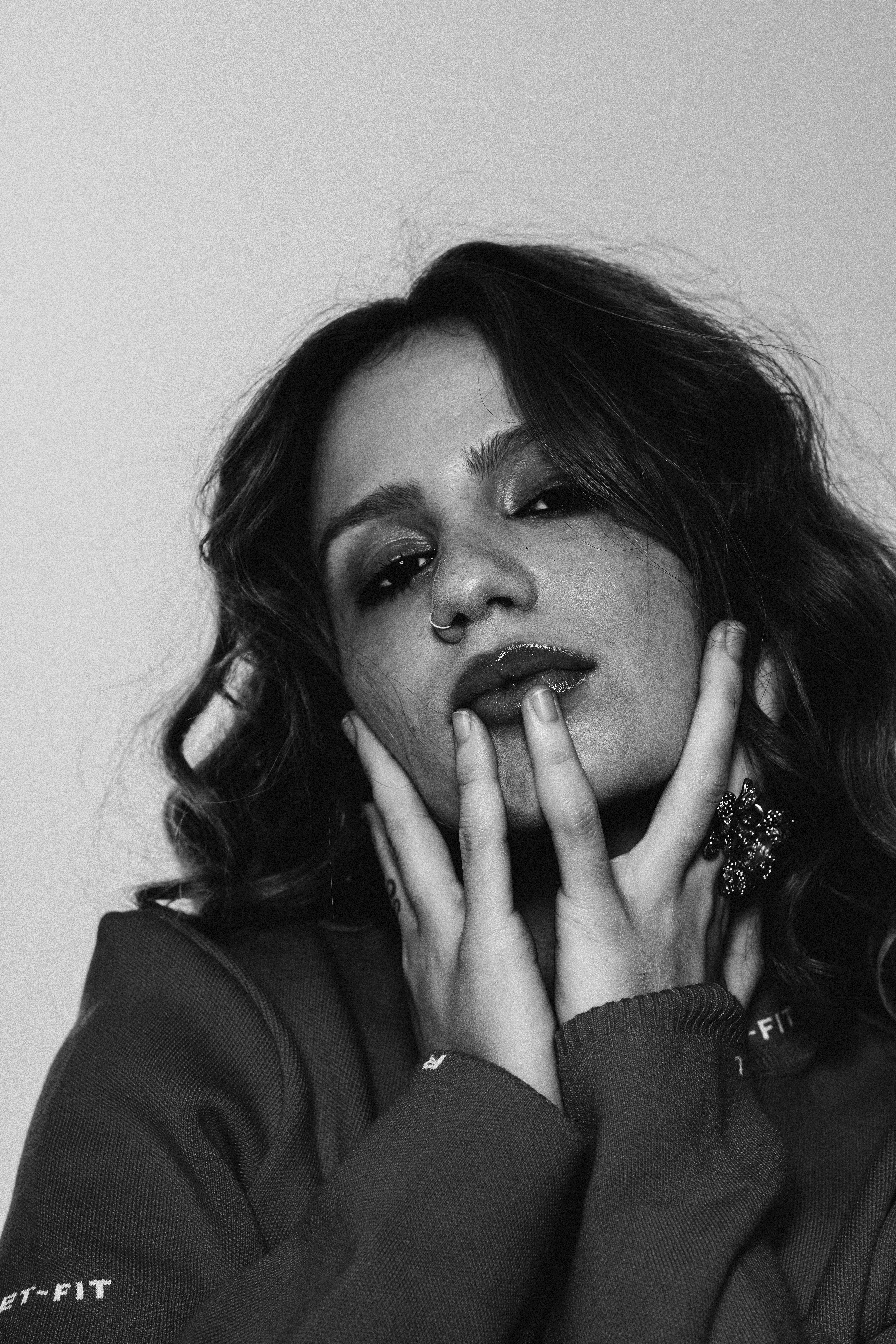 Carol Biazin posando para foto em preto e branco com as mãos no rosto